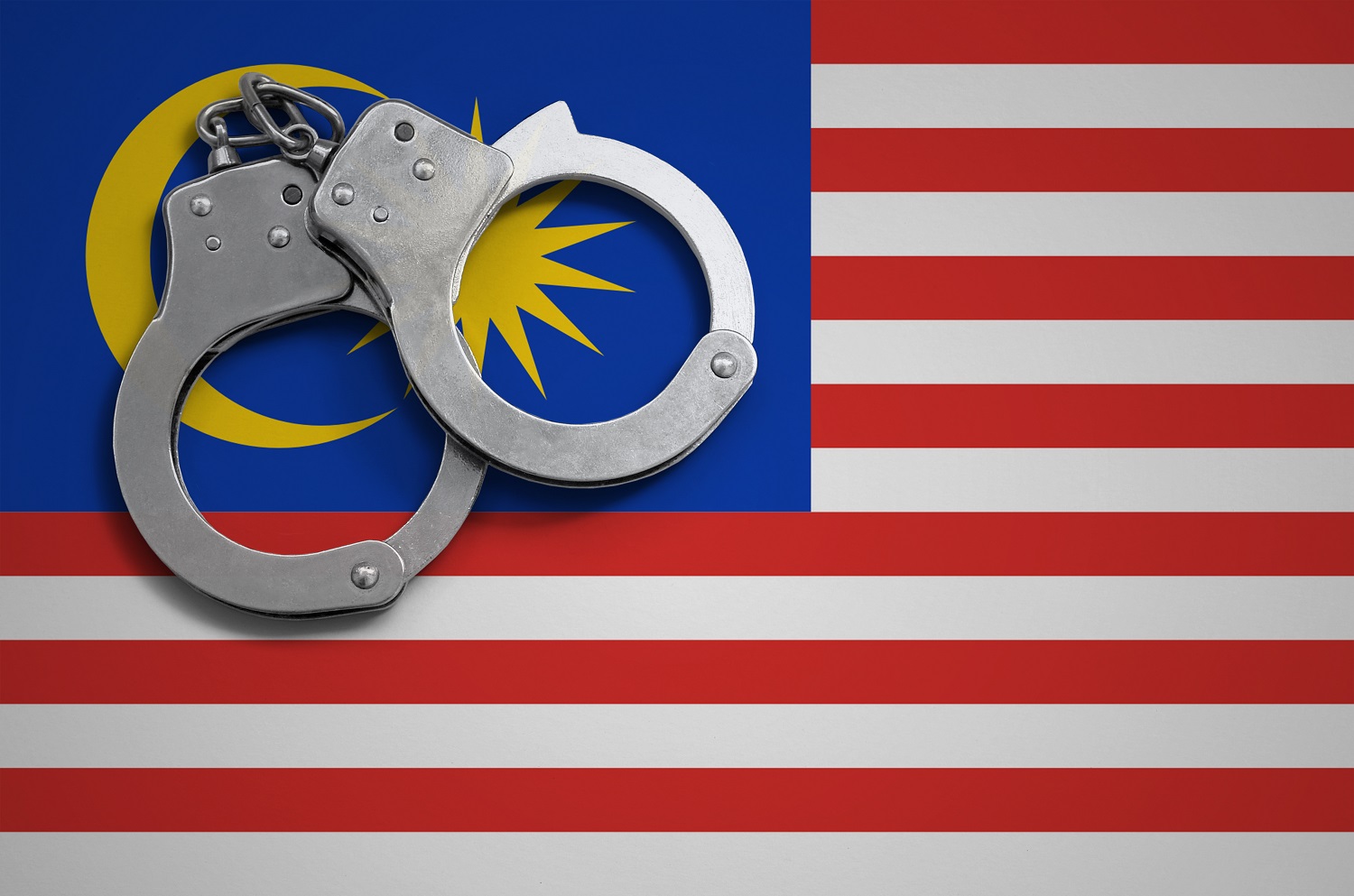 一副員警手銬放在馬來西亞國旗上。