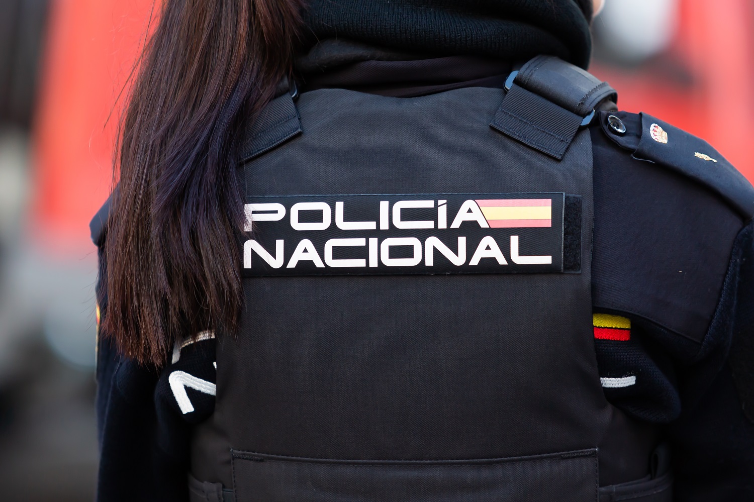 一名西班牙員警穿著寬鬆夾克，後部印有國家警察的標誌。